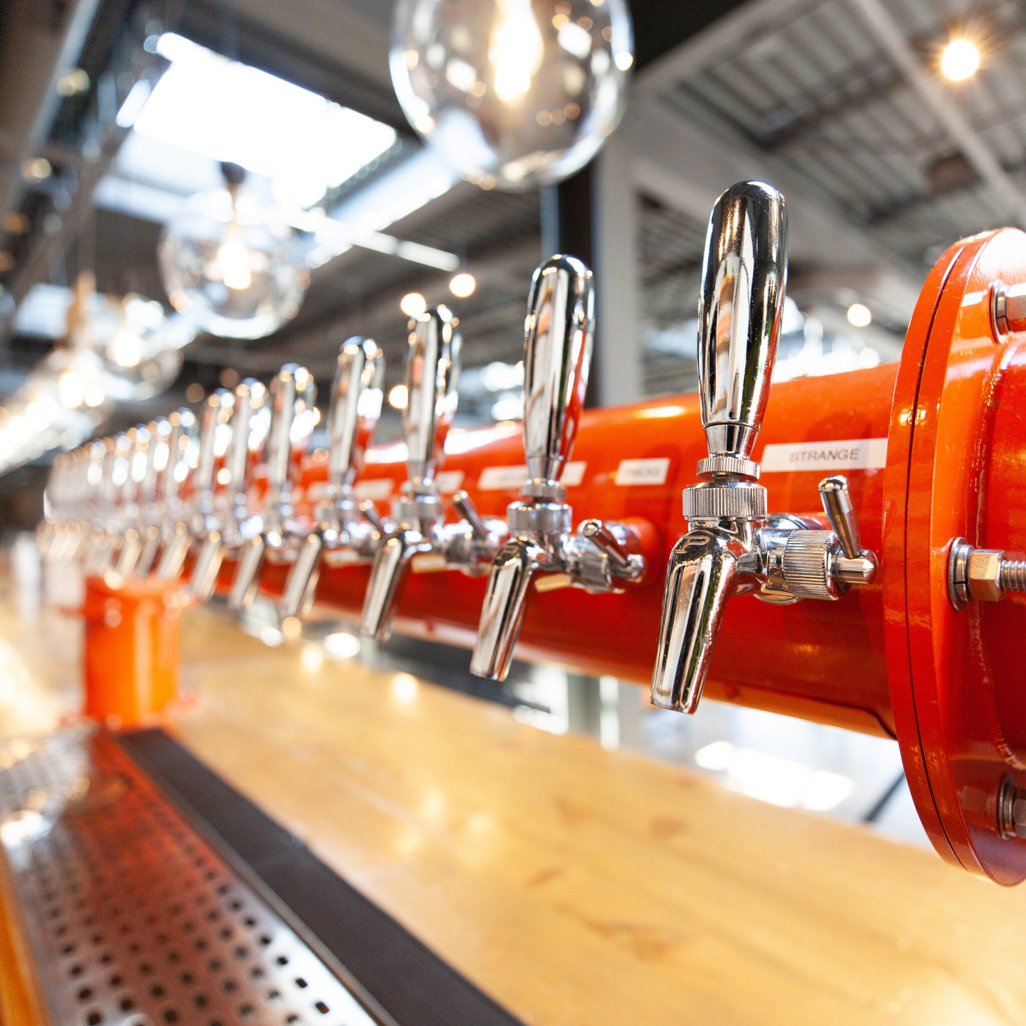 The orange tap tower and chrome faucets along the bar at the Cinderlands Warehouse