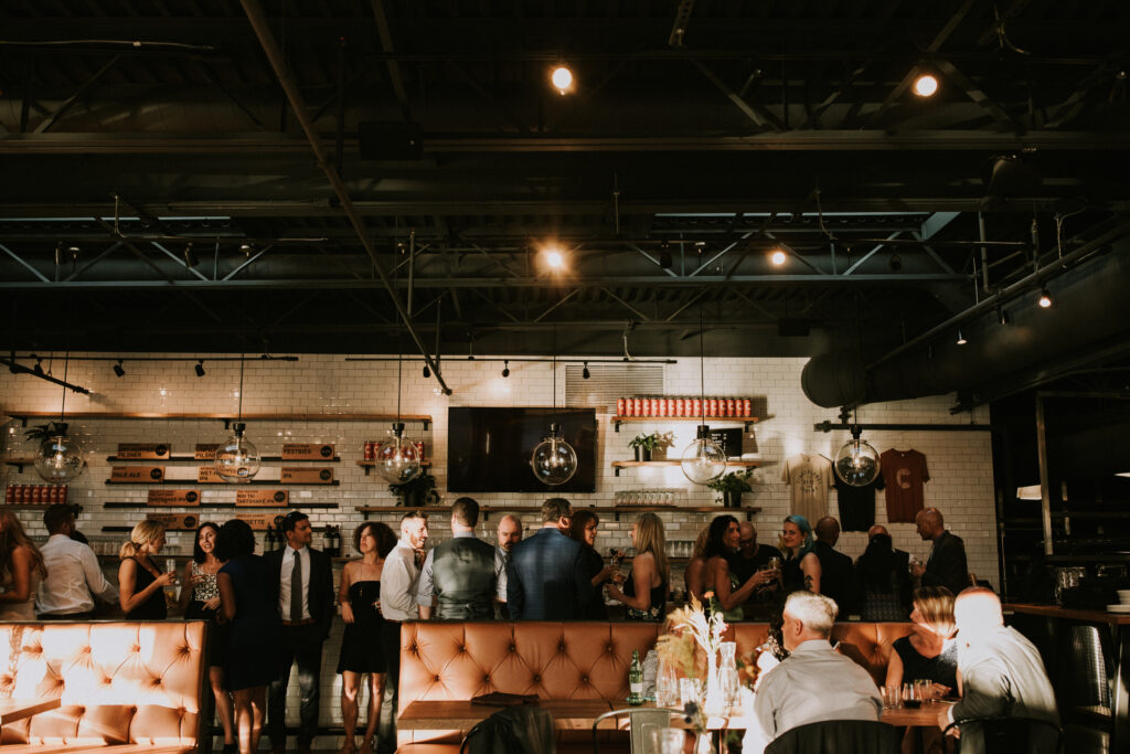 Wedding guests mingling at the bar inside the Cinderlands Warehouse