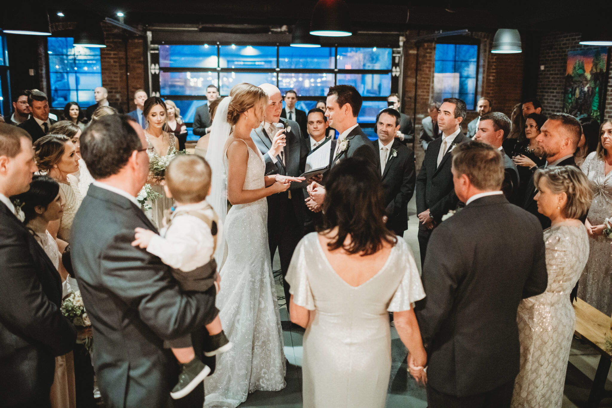 A wedding ceremony on the Upper Level of the Cinderlands Warehouse in Pittsburgh's Strip District, guests gathered around the couple