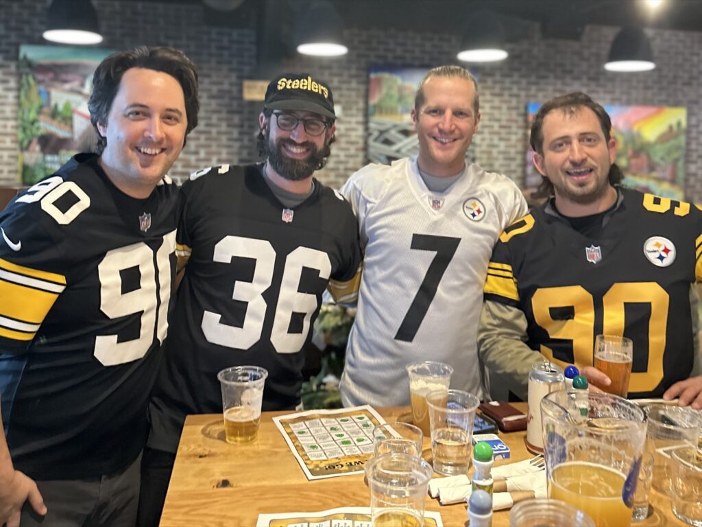 Four friends in Steelers jerseys at a table at Cinderlands Warehouse